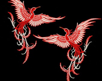 Puede incluir: Dos fénix bordados en rojo y blanco con alas y colas detalladas. Los fénix están mirando en direcciones opuestas y están colocados sobre un fondo negro.