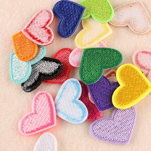 May include: Assortment of colorful embroidered felt heart patches. The patches are in various colors, including red, orange, yellow, green, blue, purple, pink, and white.