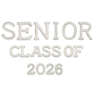 Pode incluir: Letras prateadas de strass que formam a frase "SENIOR CLASS OF 2026" sobre um fundo branco. As letras são incrustadas com pequenos strass brilhantes, criando um visual glamouroso. Ideal para formandos.