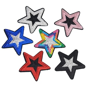May include: Six star-shaped iron-on patches with a white center and a black outline. The stars are in different colors: black, white, pink, blue, red, and rainbow.