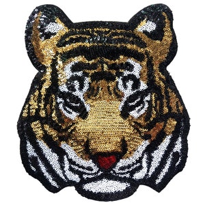 May include: A gold and black sequined tiger head applique. The tiger has a white stripe down its nose and white stripes on its cheeks.
