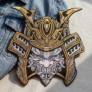 May include: Embroidered patch featuring a detailed samurai helmet design. The patch showcases gold, black, and white thread, depicting the helmet's intricate details and a fierce facial expression. The patch is likely for jackets or bags.