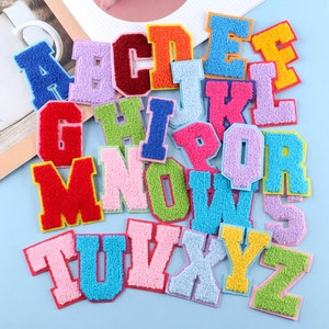 Könnte beinhalten: Ein Set mit 26 bunten Filzbuchstaben-Patches. Die Buchstaben sind in verschiedenen Farben, darunter Rot, Blau, Grün, Gelb, Pink und Lila. Die Buchstaben sind alle in Großbuchstaben und alphabetisch geordnet.
