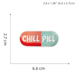May include: An embroidered iron-on patch shaped like a pill with the words "CHILL PILL" in white thread on a red and blue background. The patch measures 6.6 cm by 2.7 cm.
