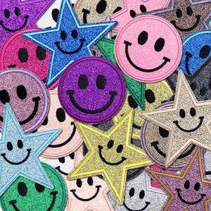 Puede incluir: Una colección de parches brillantes en varias formas y colores. Los parches incluyen caras sonrientes y estrellas, con colores como azul, morado, rosa y dorado. Cada parche tiene un contorno negro y una cara sonriente.