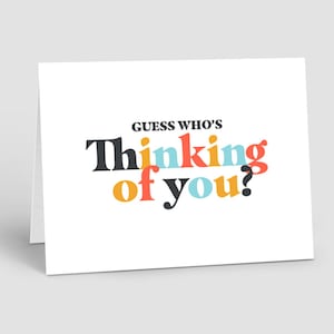 May include: A white card with the text "Guess who's thinking of you?" in black, orange, red, and blue letters.