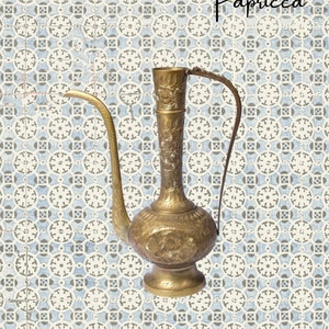 May include: A gold metal pitcher with intricate floral designs and a spout. The pitcher is on a background of blue and white patterned tiles.