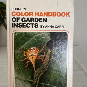 May include: A vintage book titled "Rodale's Color Handbook of Garden Insects" by Anna Carr. The cover features a vibrant image of insects on a green leaf. The book has an orange and white border with the text "Over 300 Full-Color Photographs".