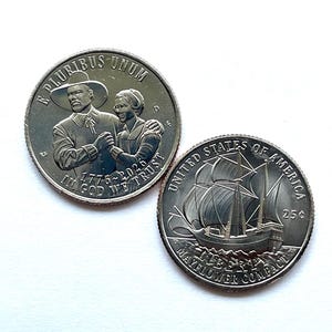May include: Two silver-colored United States quarter coins. One coin features a man and woman in historical attire with the text E PLURIBUS UNUM, 1776-2026, and IN GOD WE TRUST. The other coin shows a sailing ship with UNITED STATES OF AMERICA, 25¢, LIBERTY, and MAYFLOWER COMPACT.