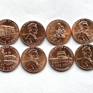 May include: Eight copper-colored United States one-cent coins. The coins feature images of Abraham Lincoln and various historical landmarks. The year 2009 is visible on several coins. The words "United States of America" and "One Cent" are also visible.