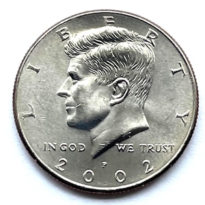 May include: A silver Kennedy half dollar coin. The obverse features a profile of John F. Kennedy, with the inscriptions "LIBERTY" and "IN GOD WE TRUST". The year "2022" is visible.