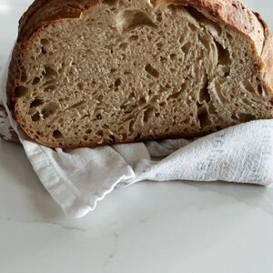May include: A close-up of a freshly baked loaf of bread, sliced in half, revealing a light brown, airy crumb with a slightly crispy crust.