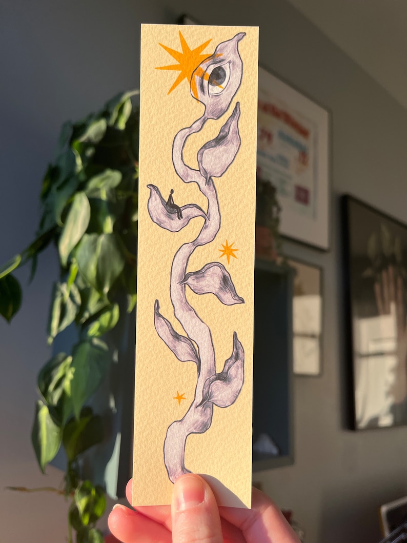 May include: A hand-drawn illustration of a stylized plant with a large eye at the top. The plant is drawn in shades of purple and gray on a yellow background. There are small yellow stars scattered around the plant.