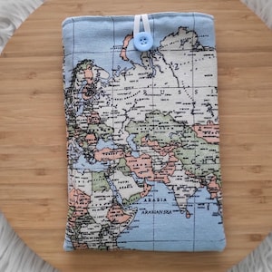 May include: A light blue fabric case featuring a world map design with a button closure. The map displays continents and countries in various colors. The case is rectangular and appears to be for a tablet or e-reader.