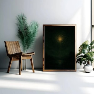 May include: A framed artwork with a dark green background and a bright yellow, starburst-like design. The artwork is in a wooden frame and is displayed next to a wooden chair, a vase with green leaves, and a potted plant.