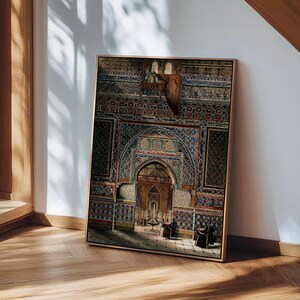 May include: Framed print of an ornate architectural interior with intricate tilework in shades of blue, red, and green. The artwork depicts a detailed archway and figures, set in a room with a light source. The frame is a light brown color.
