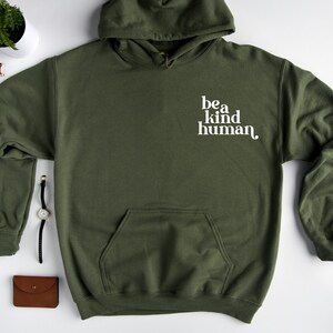 May include: A green hooded sweatshirt with a white pocket and the text "be a kind human" printed on the front.