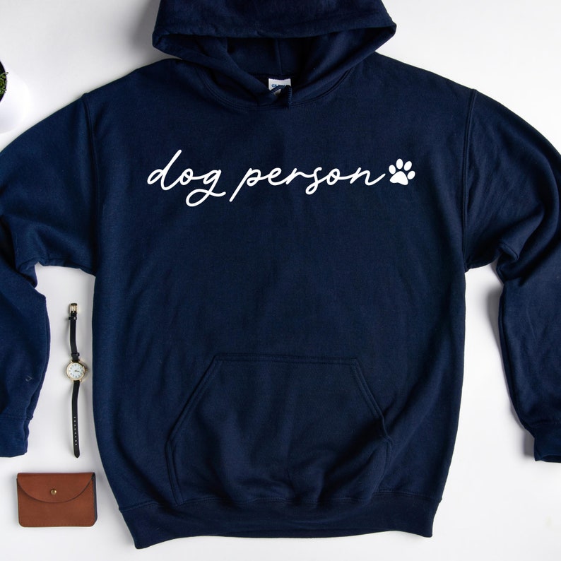 May include: A navy blue hooded sweatshirt with a white paw print and the text "dog person" in white cursive.
