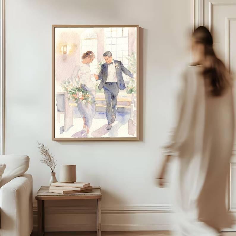 May include: A framed watercolor painting depicts a wedding scene with a couple walking. The artwork features soft pastel colors, with the bride holding a bouquet. The painting is displayed on a white wall, with a blurred figure in the foreground.
