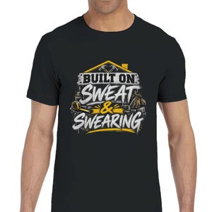 May include: A black short-sleeved t-shirt featuring a graphic design with the text "BUILT ON SWEAT & SWEARING" in white and yellow. The design includes illustrations of a house outline, crossed hammers, a tape measure, and a work glove.