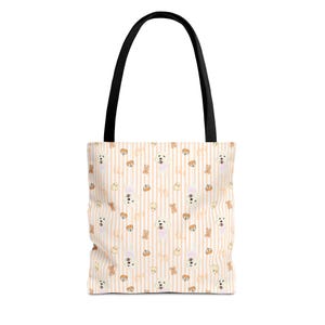 Puede incluir: Un bolso tote blanco con asa negra. El bolso presenta un patrón repetido de perros blancos, fantasmas y lazos sobre un fondo a rayas melocotón claro. El bolso está diseñado para transportar objetos.