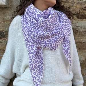 May include: A white fluffy sweater with a purple and white leopard print scarf.