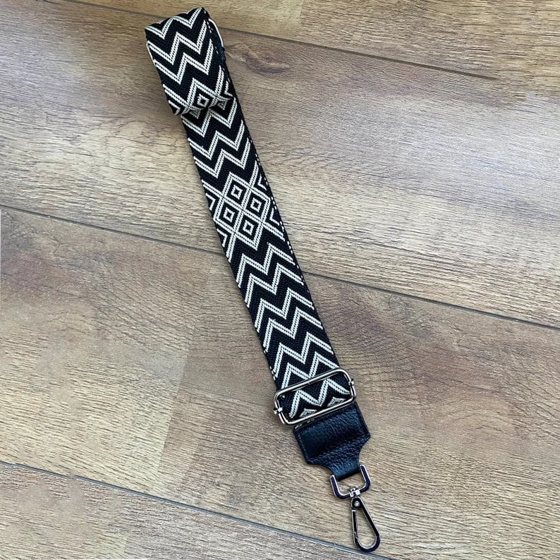 May include: Black and white patterned fabric strap with a silver hook and a black leather loop.