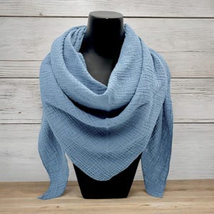 Könnte beinhalten: Ein hellblauer Schal aus Baumwollgaze. Der Schal ist gefaltet und über einen schwarzen Mannequin-Kopf gelegt. Der Schal ist weich und texturiert.