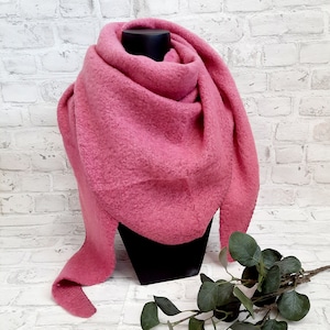 Op de afbeelding: Een roze pluche sjaal gedrapeerd over een mannequin. De sjaal is gemaakt van een zacht, getextureerd materiaal en heeft een driehoekige vorm.