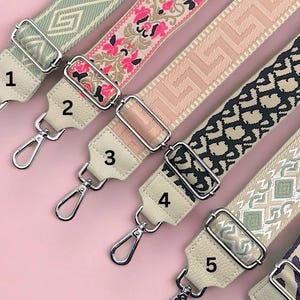 Pode incluir: Uma variedade de cinco alças decorativas para bolsas com vários padrões. As alças apresentam designs em tons de verde, rosa, bege, preto e roxo. Cada alça tem uma extremidade de couro creme com um fecho de metal prateado.