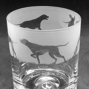 May include: A frosted glass tumbler with a silhouette of a dog etched on the side. The dog is running and has a long tail. The glass is clear and has a smooth surface.