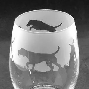 May include: A frosted glass wine glass with a silhouette of two dogs etched into the side. The dogs are black and appear to be running.