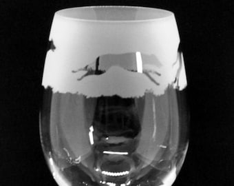 Könnte beinhalten: Ein klares Weinglas aus Glas mit einem mattierten Design eines laufenden Hundes. Das Glas hat einen langen Stiel und einen runden Boden.