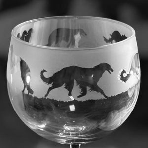May include: A clear wine glass with a black and white design. The glass has a frosted band with silhouettes of dogs running across a grassy field. The stem and base are clear, creating a classic look.