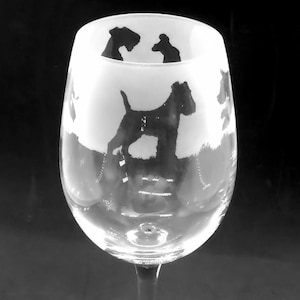 Op de afbeelding: Een helder glazen wijnglas met een mat ontwerp van zwarte silhouet honden. Het glas heeft een lange steel en een ronde voet.