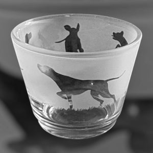 May include: A frosted glass tumbler with a silhouette of a dog etched on the side. The dog is running and has a long tail. The tumbler is clear and has a smooth surface.