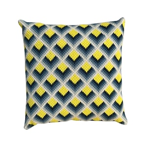 May include: Square decorative pillow with a geometric pattern. The pillow features a repeating design of yellow, navy blue, and light blue diamond shapes on a cream background. The pillow has a soft, textured appearance.