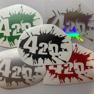 May include: Five different vinyl stickers with a splatter paint design. Each sticker features the number "420" in white lettering. The stickers are in green, black, silver, red, and iridescent.