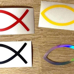 Könnte beinhalten: Vier verschiedene Versionen des Ichthys-Symbols, ein christliches Symbol, das einen Fisch darstellt. Die Symbole sind rot, schwarz, gelb und schillernd.