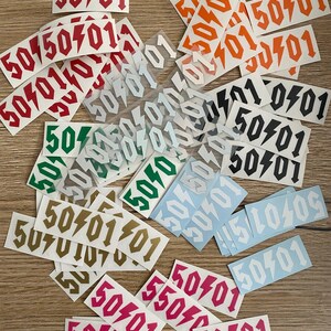 Könnte beinhalten: Eine Sammlung bunter Aufkleber mit der Nummer 50401 und einem Blitz-Design. Die Aufkleber sind in verschiedenen Farben, darunter Rot, Orange, Gelb, Grün, Blau und Pink.