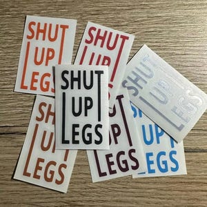 Può includere: Un set di sei adesivi con la frase "Shut Up Legs" in vari colori, tra cui nero, rosso, arancione, blu e argento.