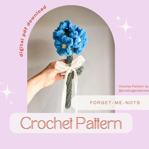 May include: A crochet pattern for a forget-me-not flower bouquet. The pattern is available as a digital PDF download. The crochet flower is blue and green and is held in a hand.