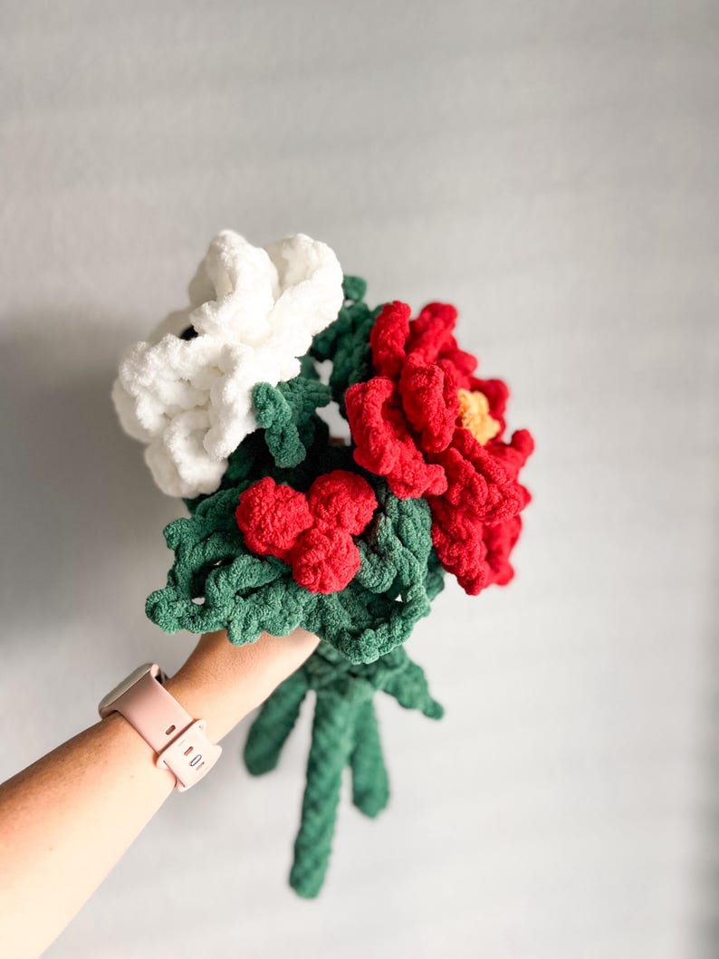 May include: A bouquet of crocheted flowers in white, red, and green. The flowers are made with yarn and have a fluffy texture.