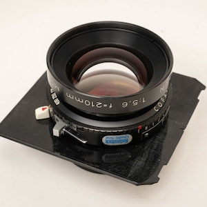 May include: A black Copal 2 150mm f/5.6 lens with a black metal lens board. The lens is marked "Copal 2" and "1:5.6 f=150mm".