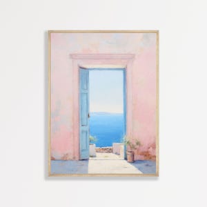 May include: A framed wall art print depicting an open light blue door set within a textured pastel pink wall. The doorway reveals a view of a bright blue sea under a clear sky, with a small potted green plant placed on the stone floor nearby.
