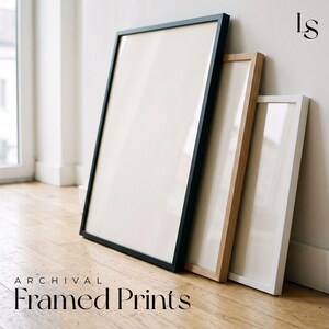 a collection of framed prints arranged on a wooden floor against a white wall.