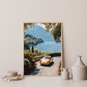 a yellow car driving down a road next to a lake