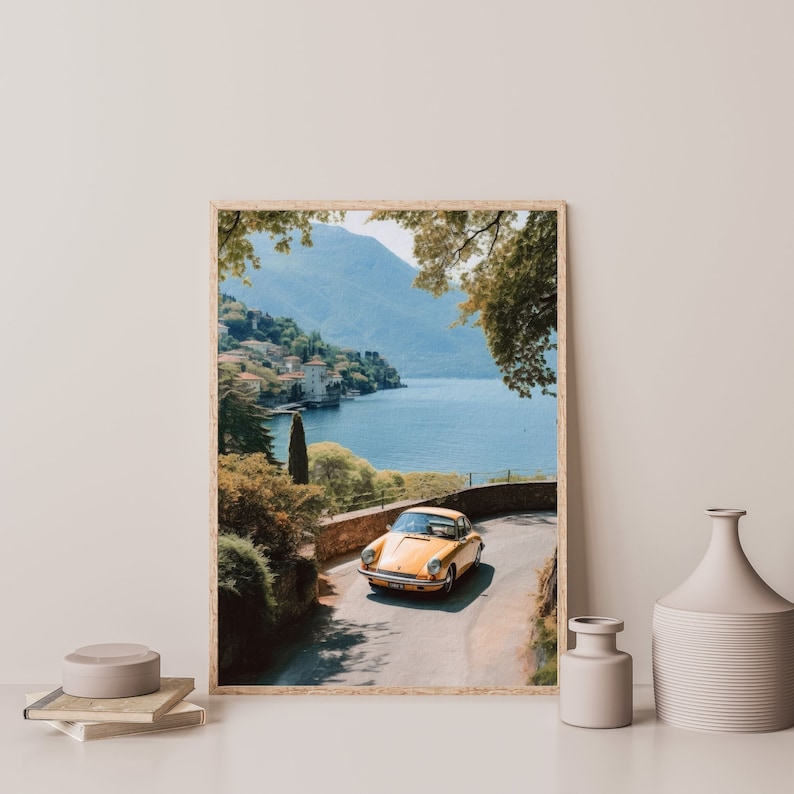 a yellow car driving down a road next to a lake