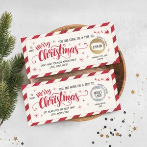 Puede incluir: Dos boletos de rascar con temática navideña con bordes a rayas rojas y blancas. Los boletos dicen "Merry Christmas" en escritura roja. Un boleto revela un viaje a Hawái, el otro a Disneylandia. Los boletos están en una bandeja de madera.