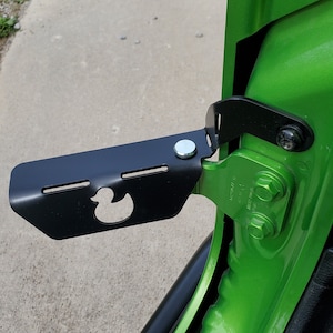 May include: A black metal step with a rubber duck cutout mounted on a green vehicle door.